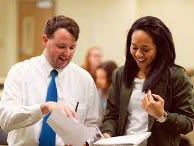 A man and woman looking at a sheet of paper. 
