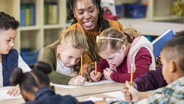 A teacher supervising four young students. 